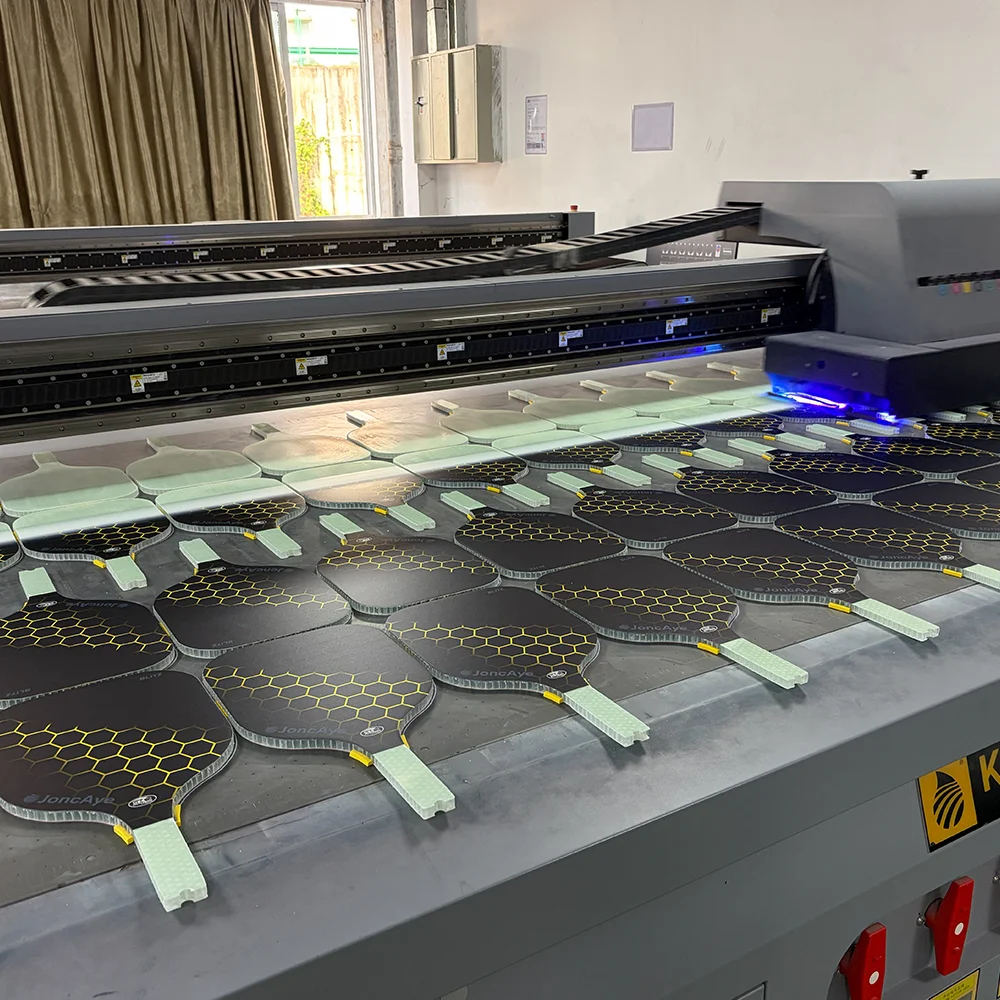 A high-precision digital printer applying vibrant, custom graphics onto fiberglass pickleball paddles, ensuring durable and sharp design reproduction.