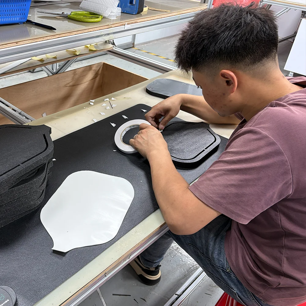 A skilled worker carefully applying high-strength adhesive to pre-cut EPP cores, ensuring a uniform bond for maximum paddle durability.