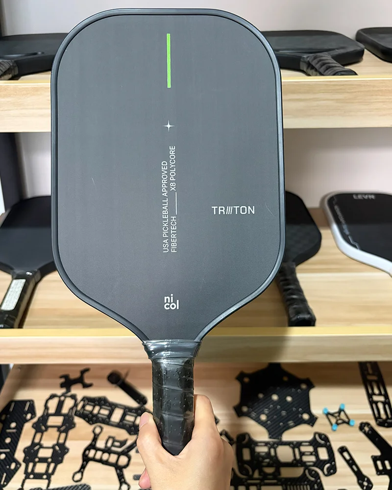 A professional pickleball paddle featuring a Toray T700 raw carbon fiber surface, known for its extreme texture, high friction, and superior spin control.